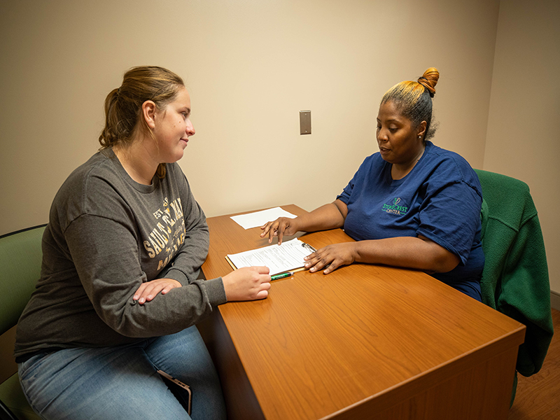 A counselor and patient work on paperwork at a desk in StoneCrest Center