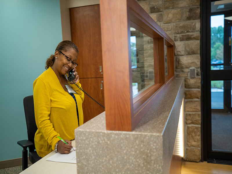 A smiling receptionist on the phone at StoneCrest Center